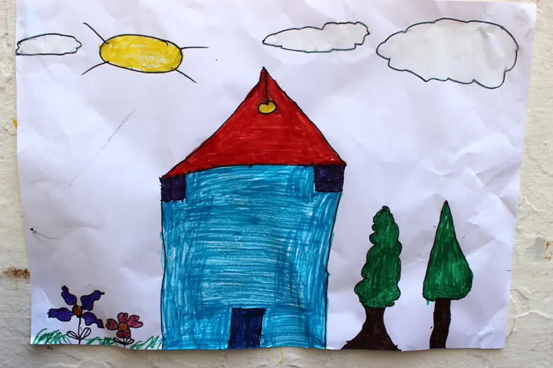 A child's drawing of a blue house with a red roof under a yellow sun, from the Healing Through Art program, Beirut, July 2014